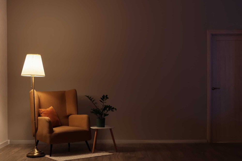 Rozsvietená lampa pri kresle na čítanie